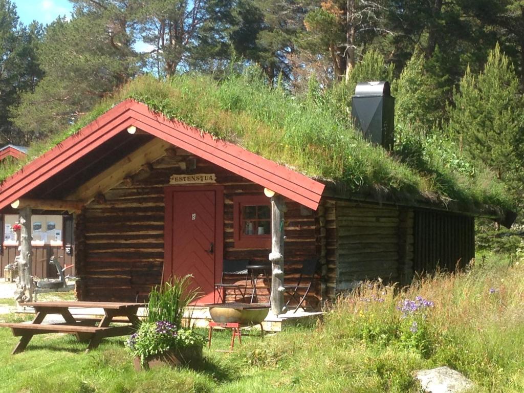 eine Hütte mit einem Grasdach mit einer Bank und einem Tisch in der Unterkunft Båtstø Camping in Elga