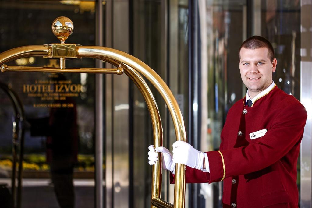 a man in red uniform holding a gold door at A Hoteli - Hotel Izvor in Arandelovac
