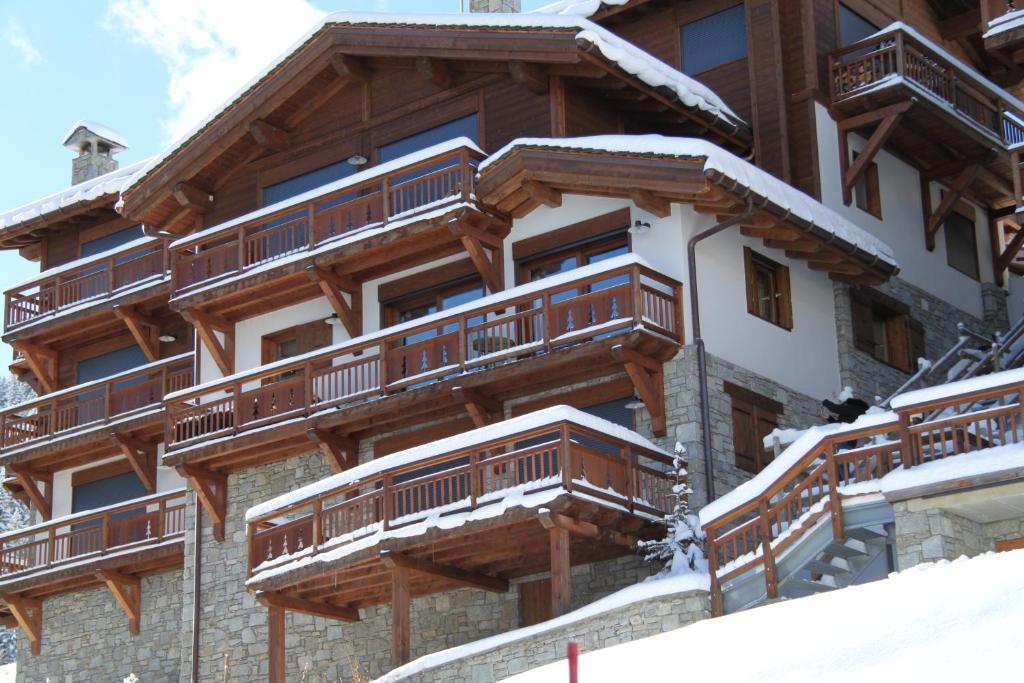ein Gebäude mit Holzbalkonen im Schnee in der Unterkunft Le Rocher Blanc A in Courchevel