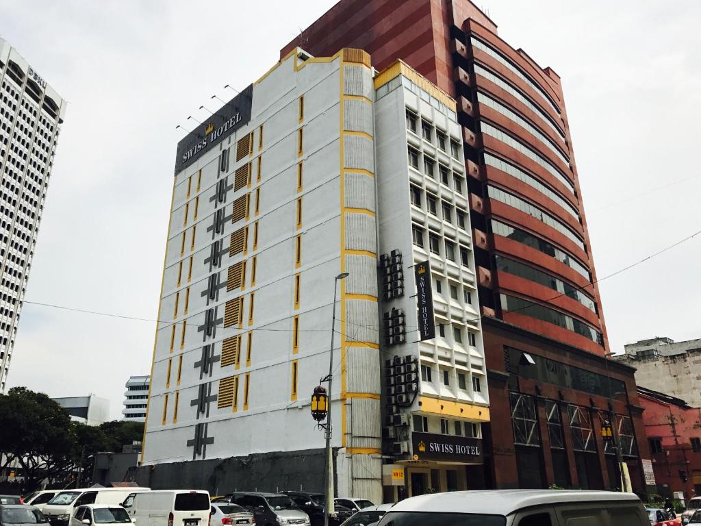 a tall building with cars parked in a parking lot at Swiss Hotel Kuala Lumpur in Kuala Lumpur