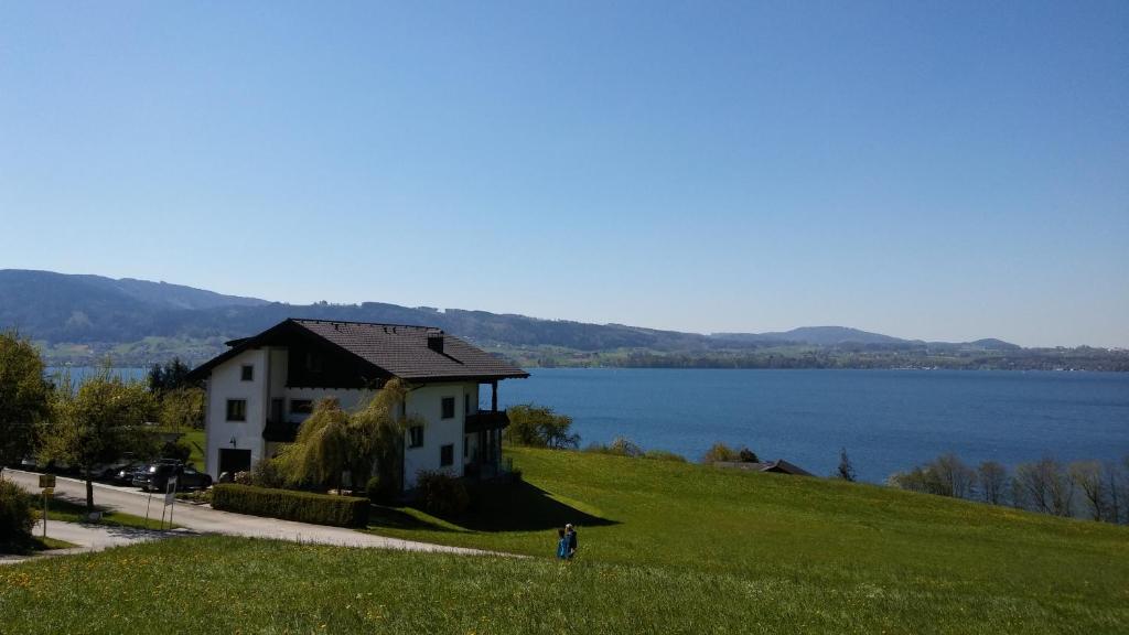 ein Haus auf einem Hügel neben einem Wasserkörper in der Unterkunft Ferienwohnung Gaigg in Weyregg