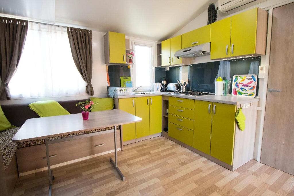 cocina con armarios amarillos y mesa en Mobile Home en Duna Verde