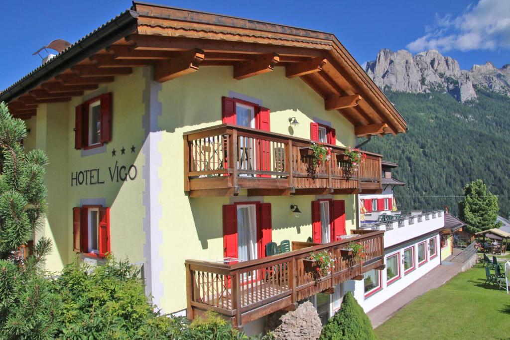 a building with wooden balconies and a mountain at Hotel Vigo in Vigo di Fassa