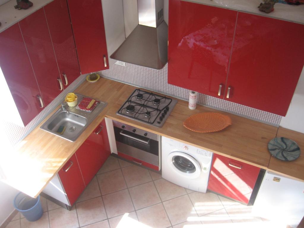 uma pequena cozinha com armários vermelhos e uma máquina de lavar roupa em Sansone em Portoferraio