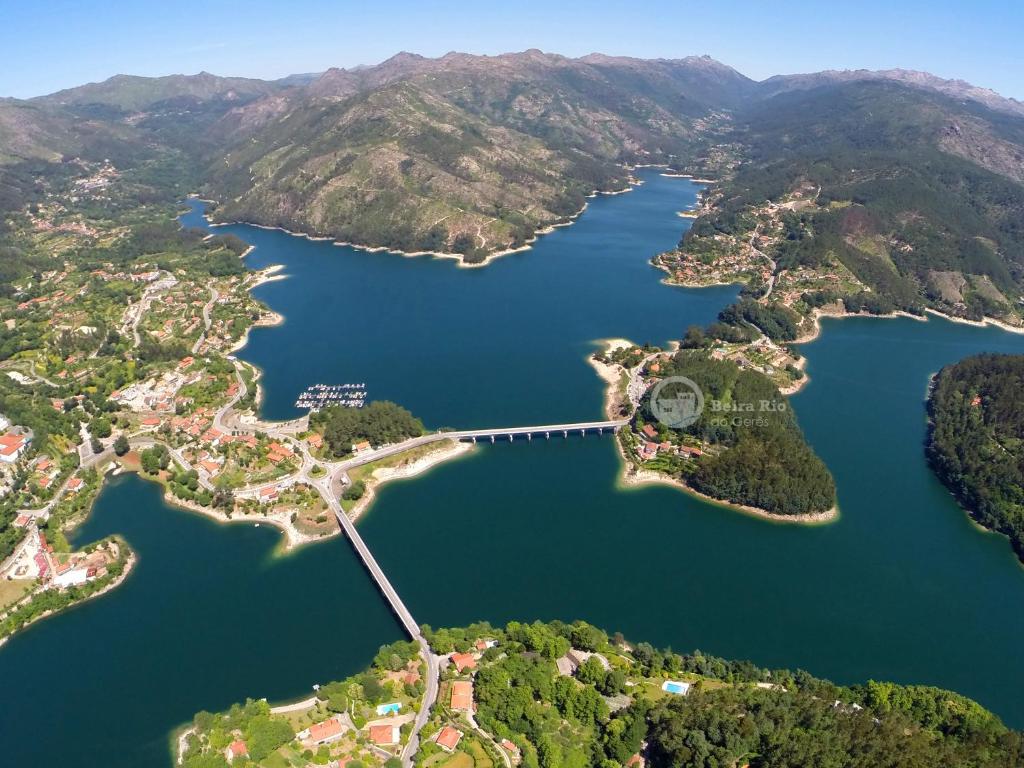 une vue aérienne sur un lac avec un pont sur celui-ci dans l'établissement Beira Rio do Gerês, à Gerês