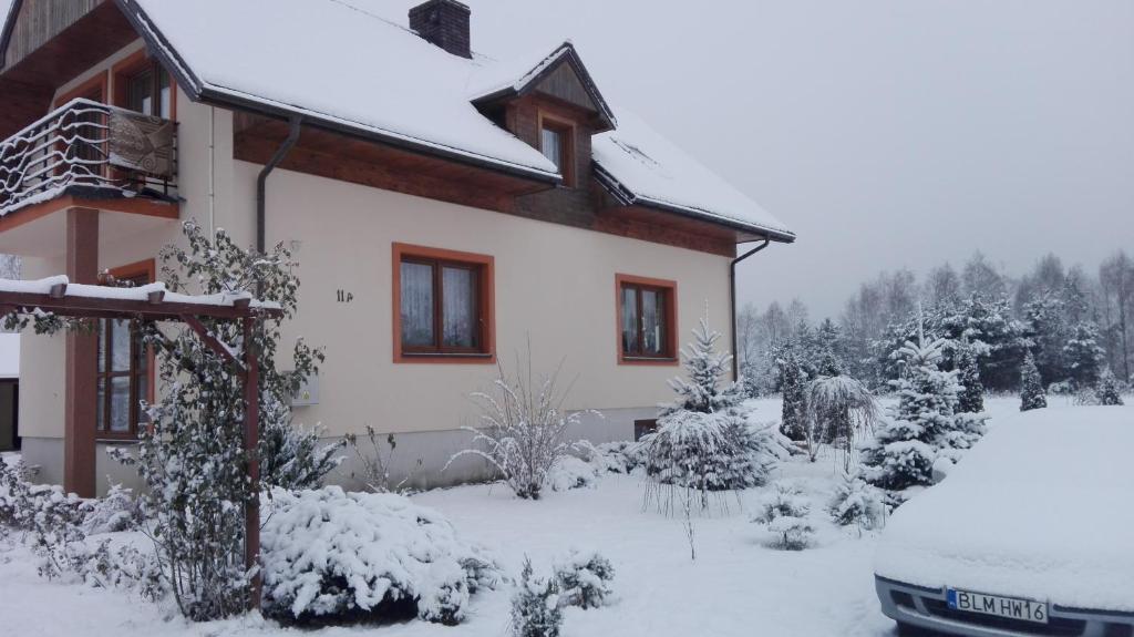 a house covered in snow with a car parked in front at Agroturystyka Pod Bocianim Gniazdem in Morgowniki