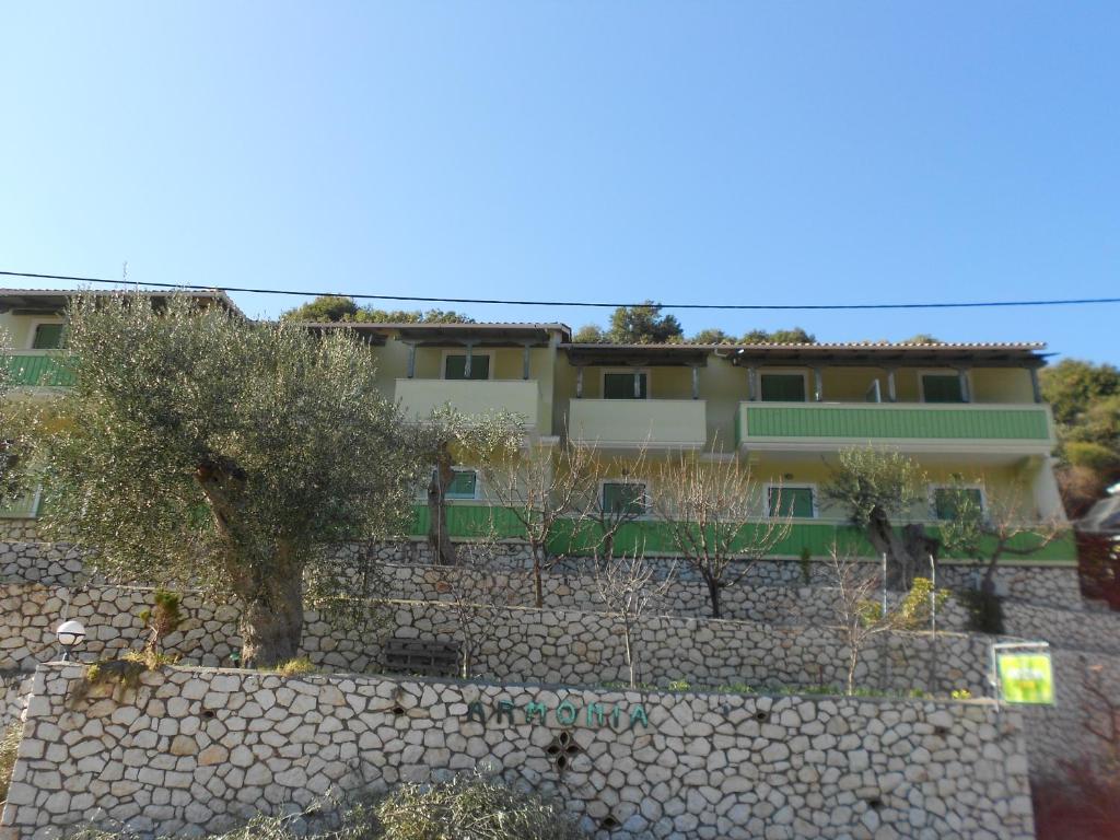 un edificio detrás de una pared de piedra con un árbol en Harmony, en Kalamitsi