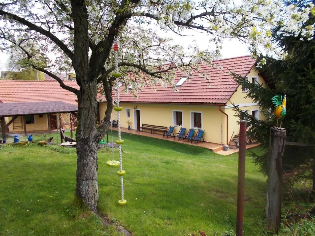 una casa con un patio con un árbol y algunos columpios en U kohouta, en Podkost