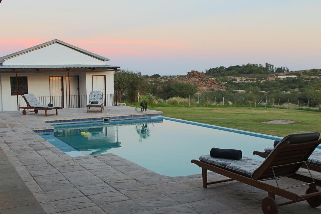 a swimming pool in front of a house at Die Bult Plaas Guesthouse in Marchand