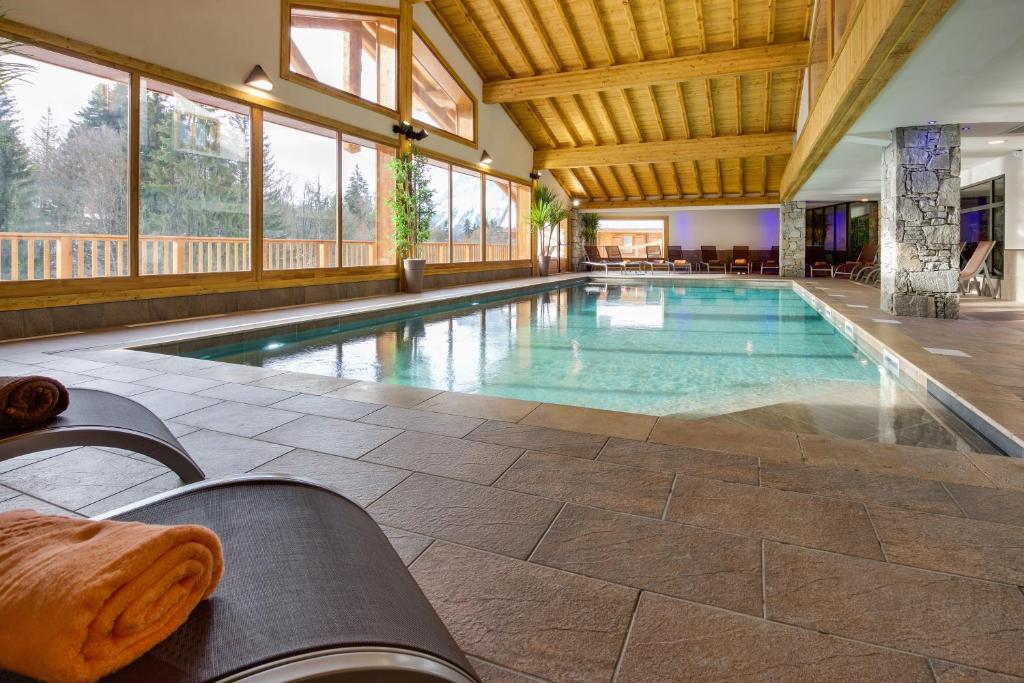 a large swimming pool in a house with a large ceiling at CGH Résidences & Spas Les Chalets de Léana in Les Carroz d'Araches