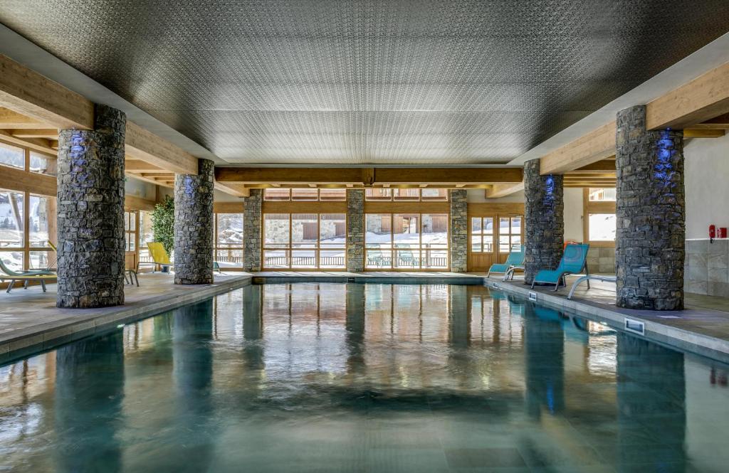 a swimming pool with pillars in a building at CGH Résidences & Spas La Grange aux fées in Valmorel