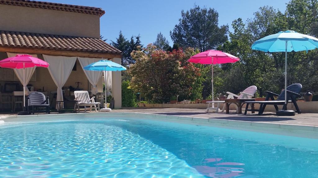 a swimming pool with two umbrellas and a table and chairs at Villa Mylena in Jouques