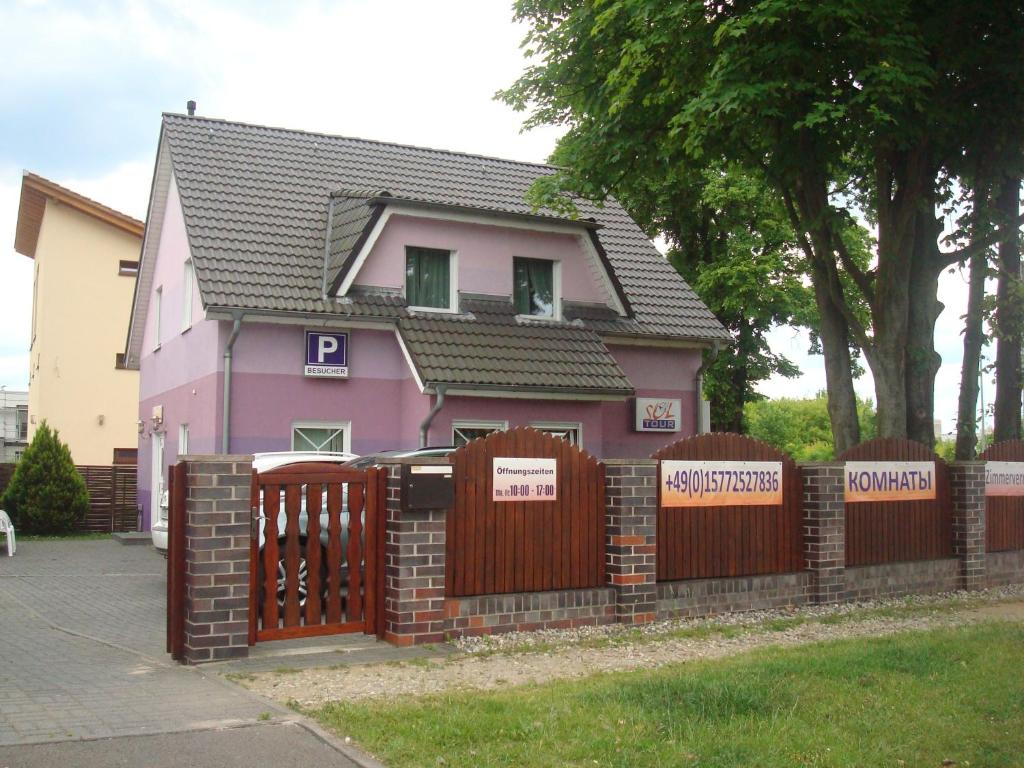 a pink house with a fence in front of it at Gästehaus Sol Tour in Ahrensfelde