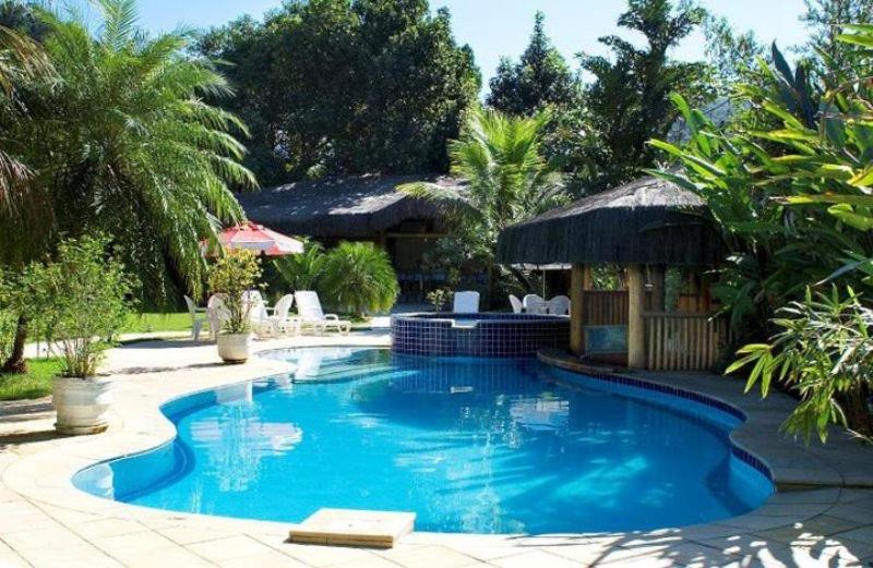 a large blue swimming pool with a gazebo at Pousada Bico Verde in Juquei