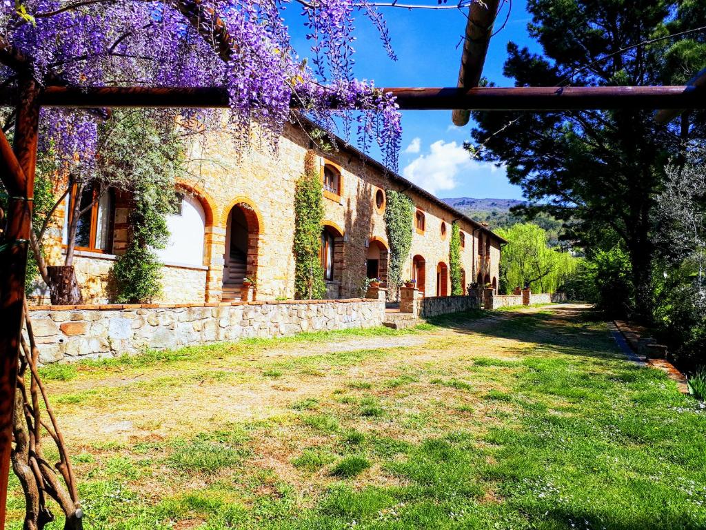 un bâtiment avec des fleurs violettes sur son côté dans l'établissement Agriturismo Antico Borgo Poggitazzi, à Loro Ciuffenna