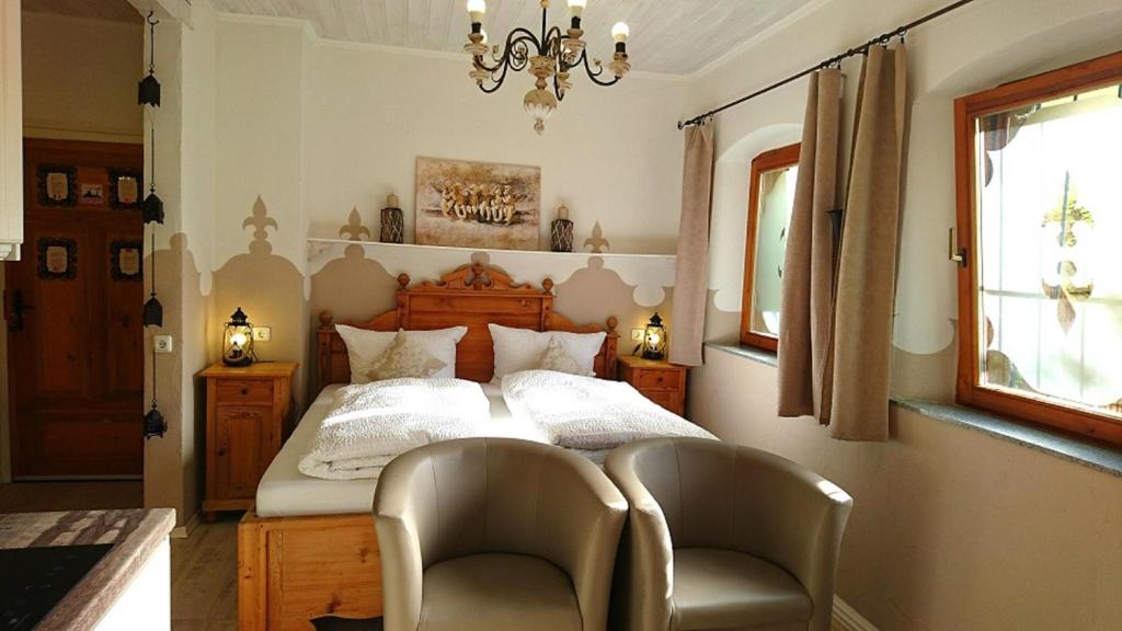 Schlafzimmer mit einem Bett mit 2 Stühlen und einem Kronleuchter in der Unterkunft Gästehaus Liebler in Rothenburg ob der Tauber