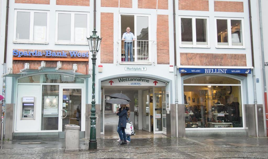 a woman walking down a street with an umbrella at Apartement mit Dachterrasse - bei Curth klingen - Teilen Sie uns Ihre Ankunfszeit mit in Düsseldorf