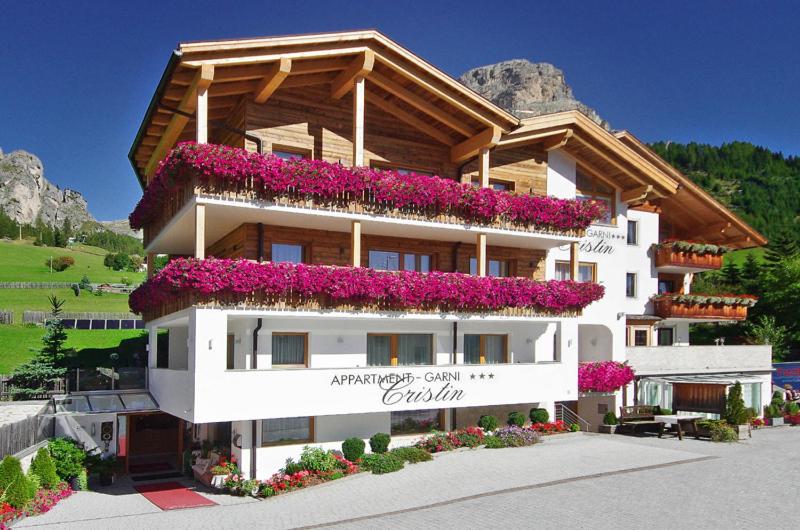 a building with flowers on the side of it at Garni Cristin & Dep Antina in Colfosco