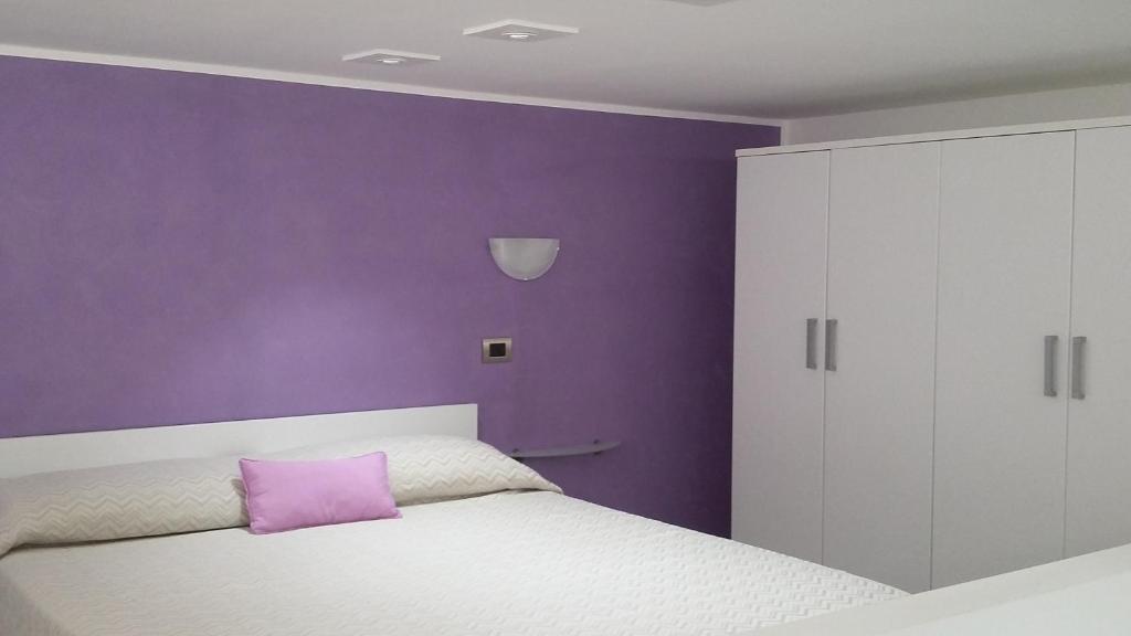 purpurowa sypialnia z białym łóżkiem i fioletową ścianą w obiekcie Taormina Rainbow House w Taominie