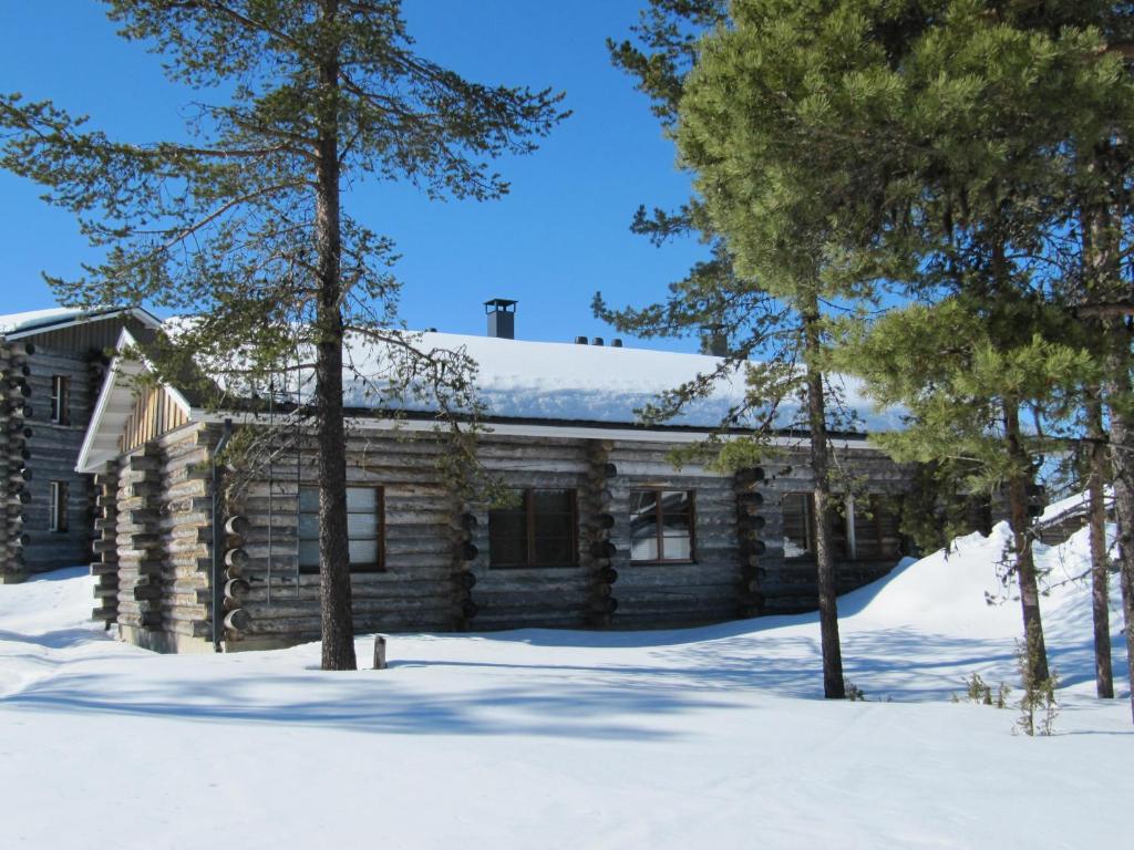 a log cabin in the snow with trees at Lapin Kutsu Log Cabins in Saariselka