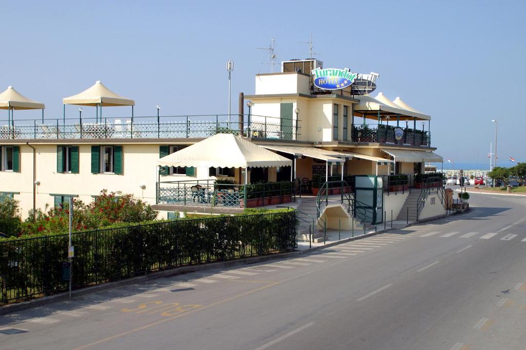 a building with umbrellas on the side of a road at Hotel Turandot in Torre del Lago Puccini