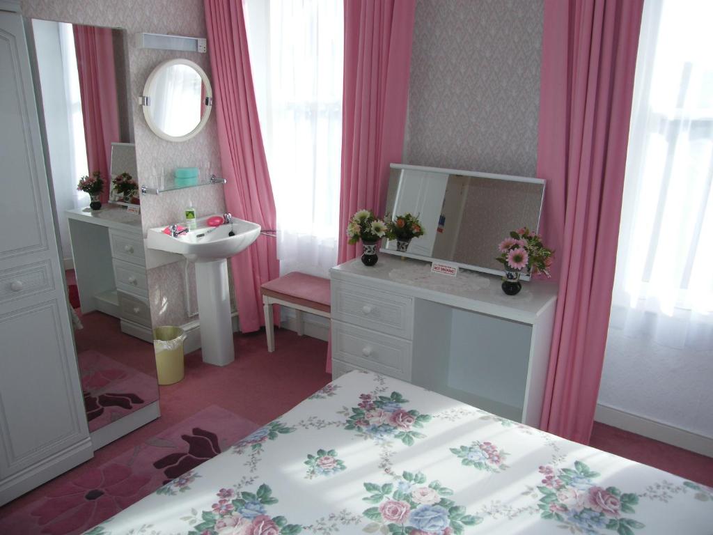 a bathroom with a bed and a sink and a mirror at El Tabora Guest House in St Peter Port