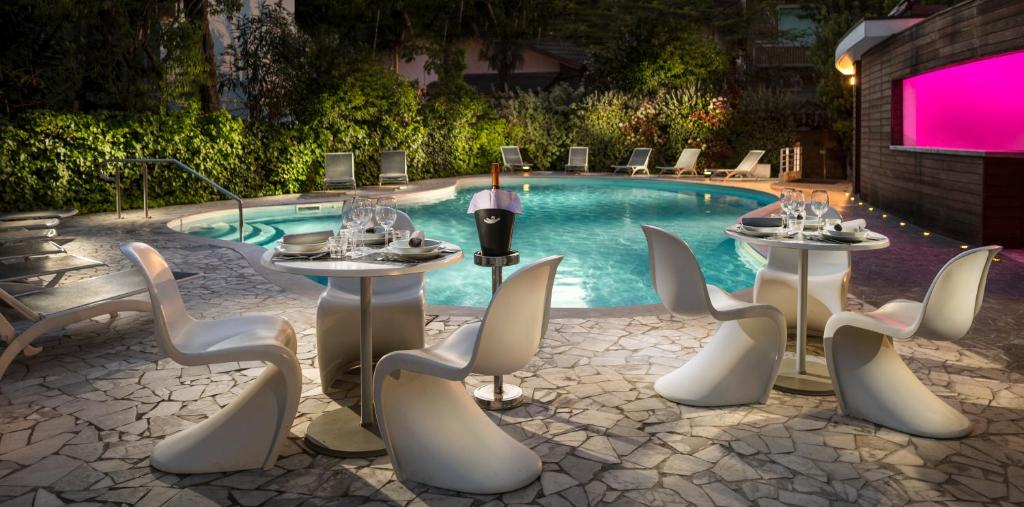 eine Gruppe von Tischen und Stühlen neben einem Pool in der Unterkunft Hotel Buona fortuna in Bellaria-Igea Marina
