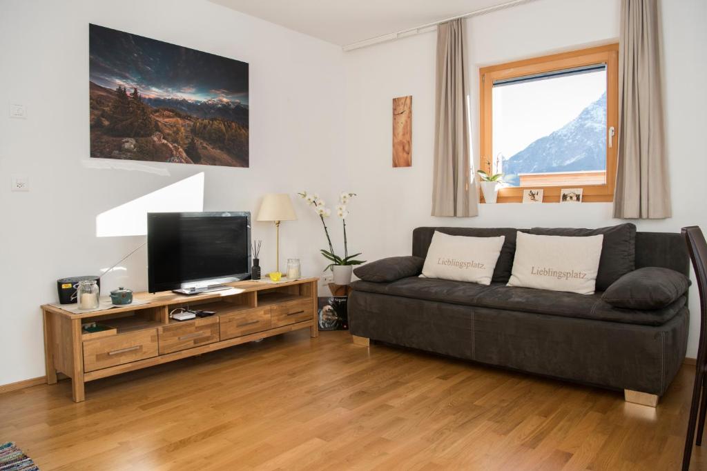 ein Wohnzimmer mit einem Sofa und einem Flachbild-TV in der Unterkunft Ferienwohnung Fionas 267 in Ftan