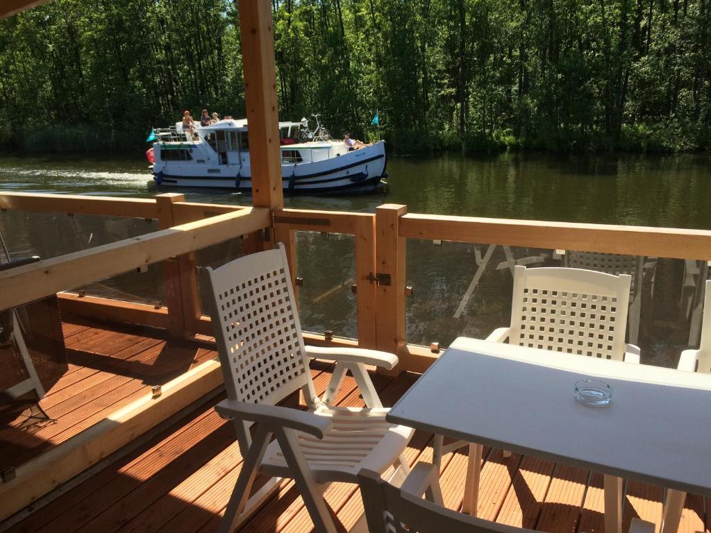 einen Tisch und Stühle auf einer Terrasse mit einem Boot im Wasser in der Unterkunft Bootshaus Mirow in Mirow