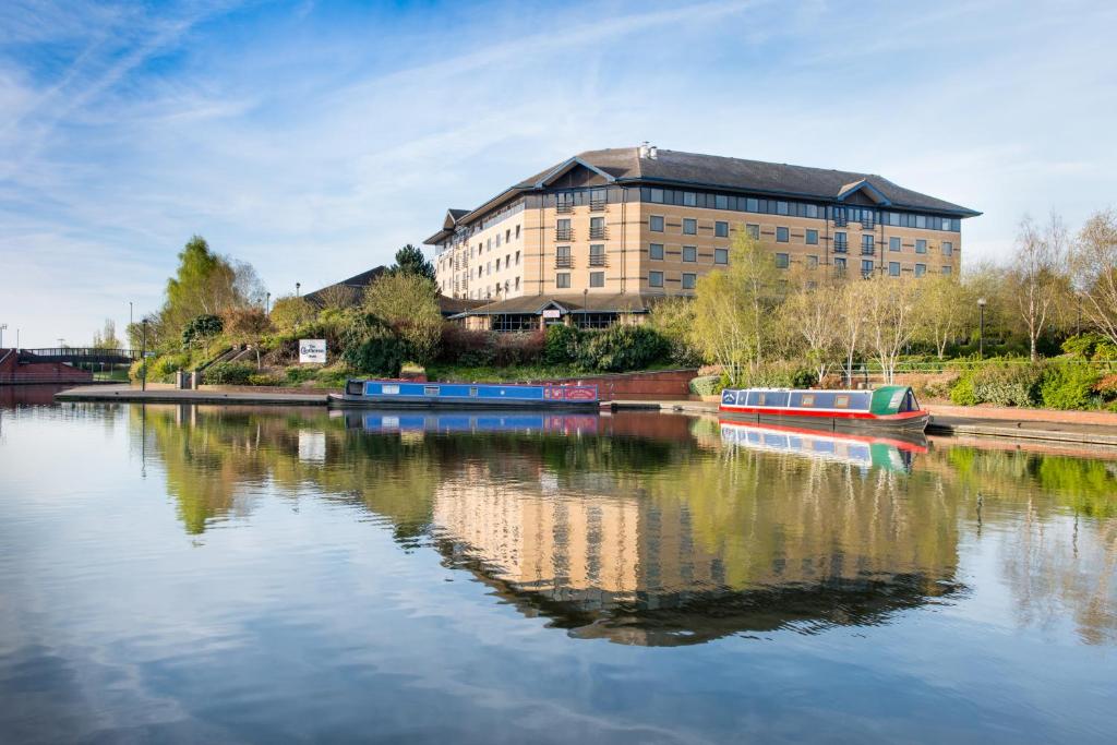 a large building next to a river with boats in it at Copthorne Hotel Merry Hill Dudley in Dudley