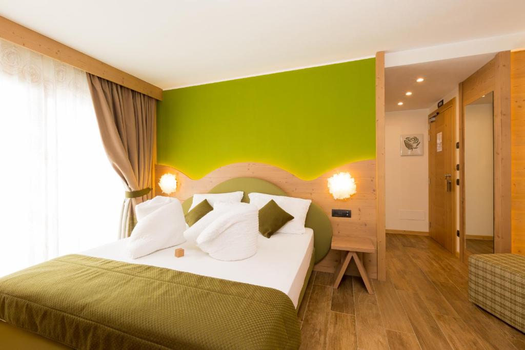 a bedroom with a large bed with a green wall at Green Rose in Livigno