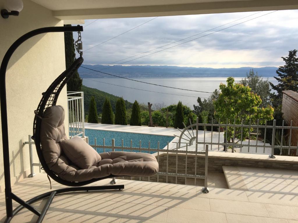 einen Stuhl auf einem Balkon mit Blick auf das Wasser in der Unterkunft Apartment Selce Kala in Mošćenička Draga