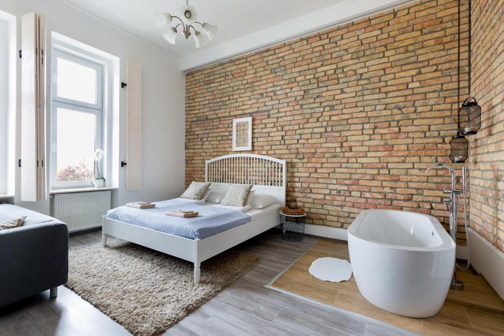 a bedroom with a brick wall and a bed and a tub at Buda Castle Apartment in Budapest