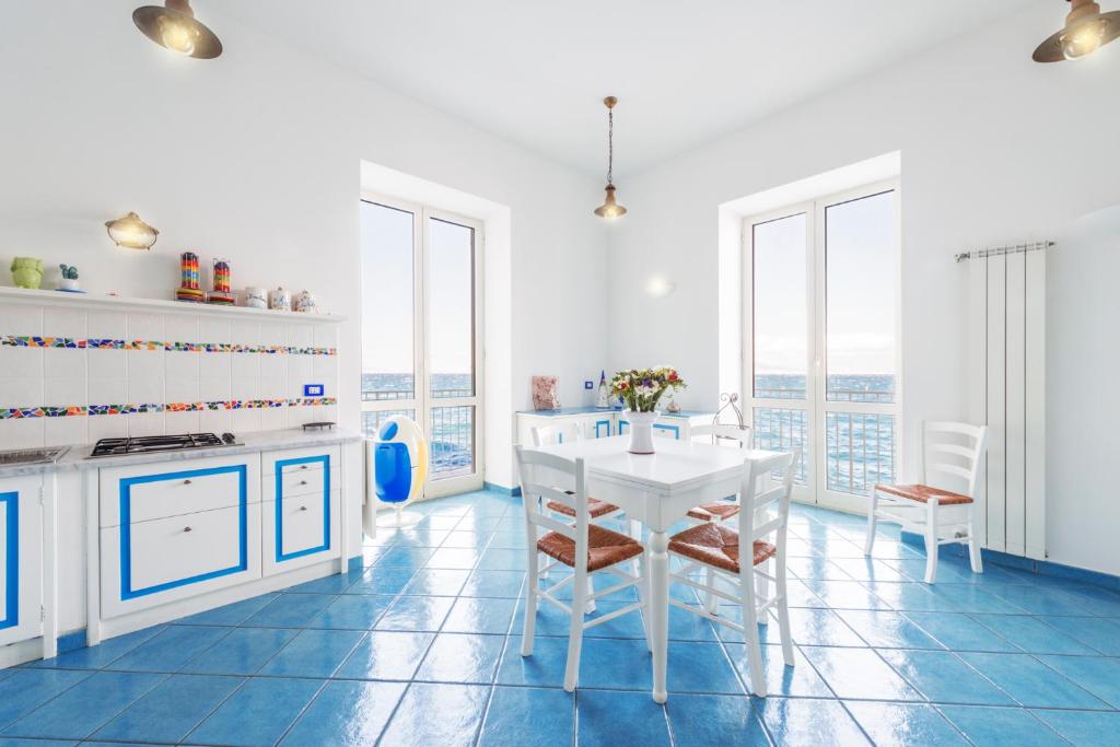 uma cozinha com uma mesa branca, cadeiras e janelas em La Luella em Sorrento