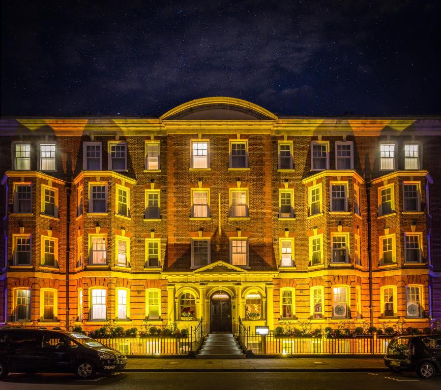 um grande edifício de tijolos com luzes acesas à noite em Ten Manchester Street Hotel em Londres