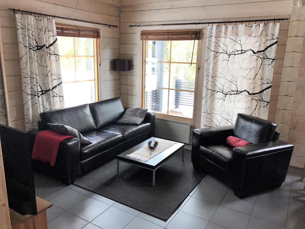 a living room with two leather couches and a table at Rukan Sarastus in Ruka