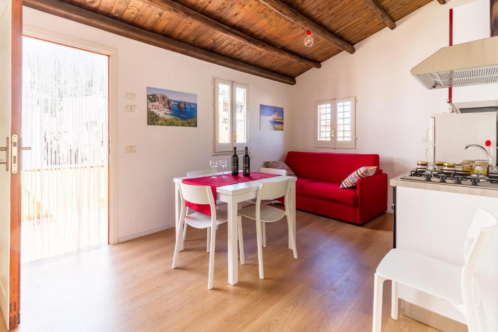 a kitchen and living room with a table and a red couch at Casa Turano in Castellammare del Golfo