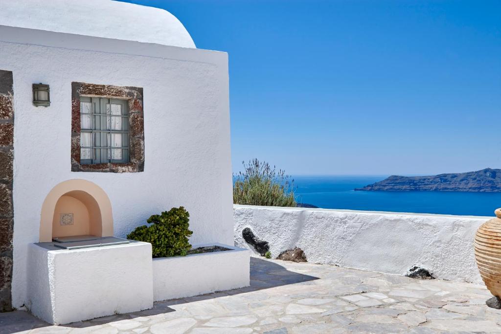 a white building with a window and a view of the ocean at Nautilus Villa in Firostefani