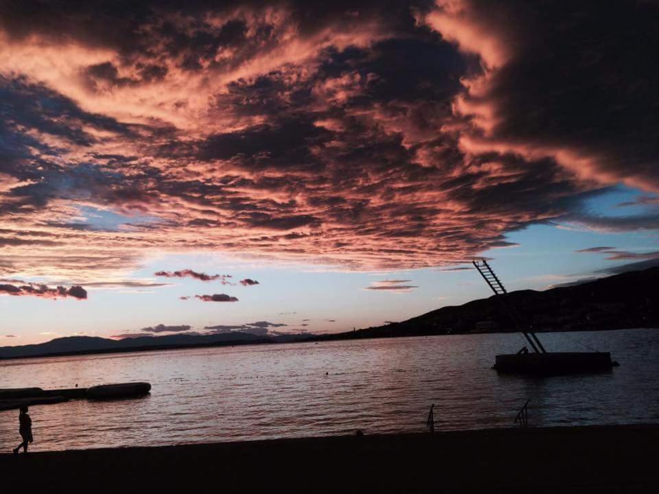 a sunset over a body of water with a boat at Roko Apartments in Selce