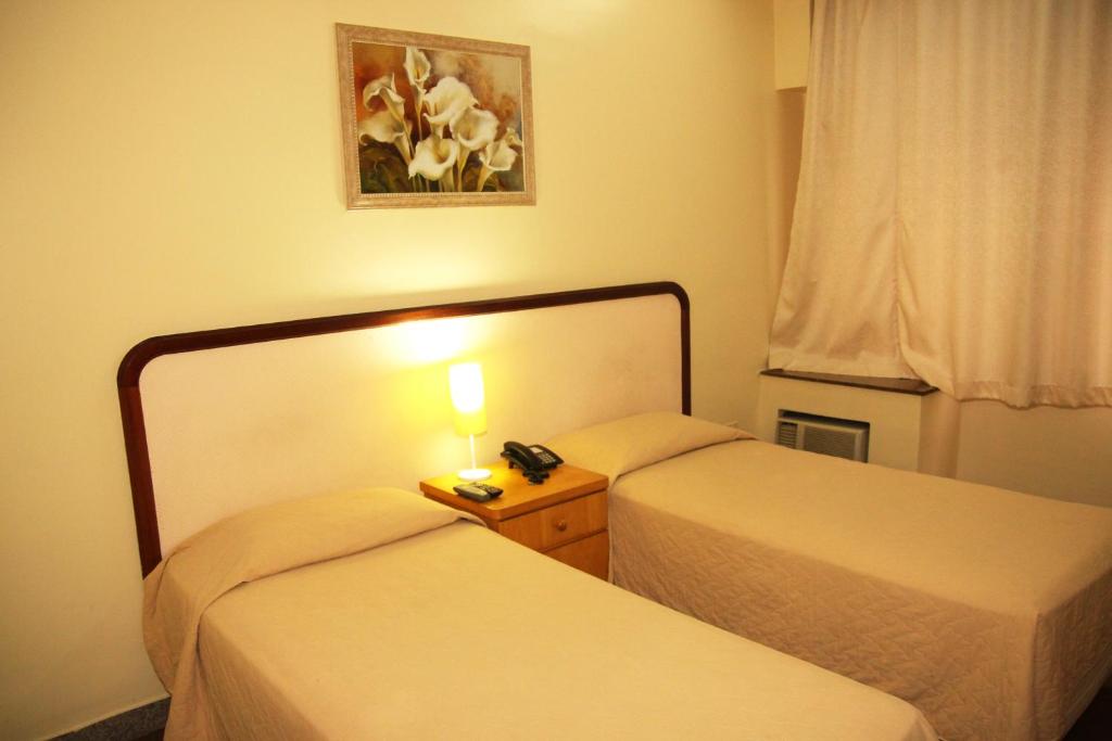 2 Betten in einem Hotelzimmer mit einer Lampe dazwischen in der Unterkunft Free Palace Hotel in São Paulo