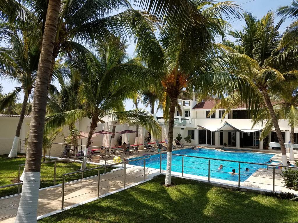 una piscina con palmeras frente a una casa en Casa Margarita Hotel And Paradise, en Las Lisas