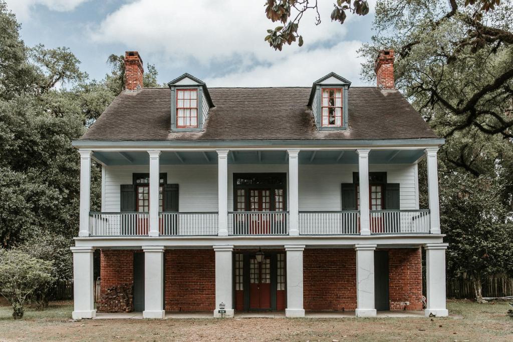 an old brick house with white columns at Maison Mouton Bed & Breakfast in Lafayette