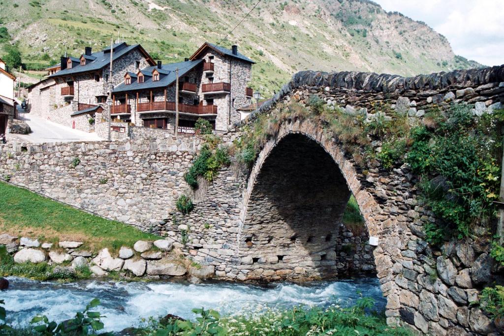 eine Steinbrücke über einen Fluss neben einem Berg in der Unterkunft Apartamentos Les Picardes in Espot