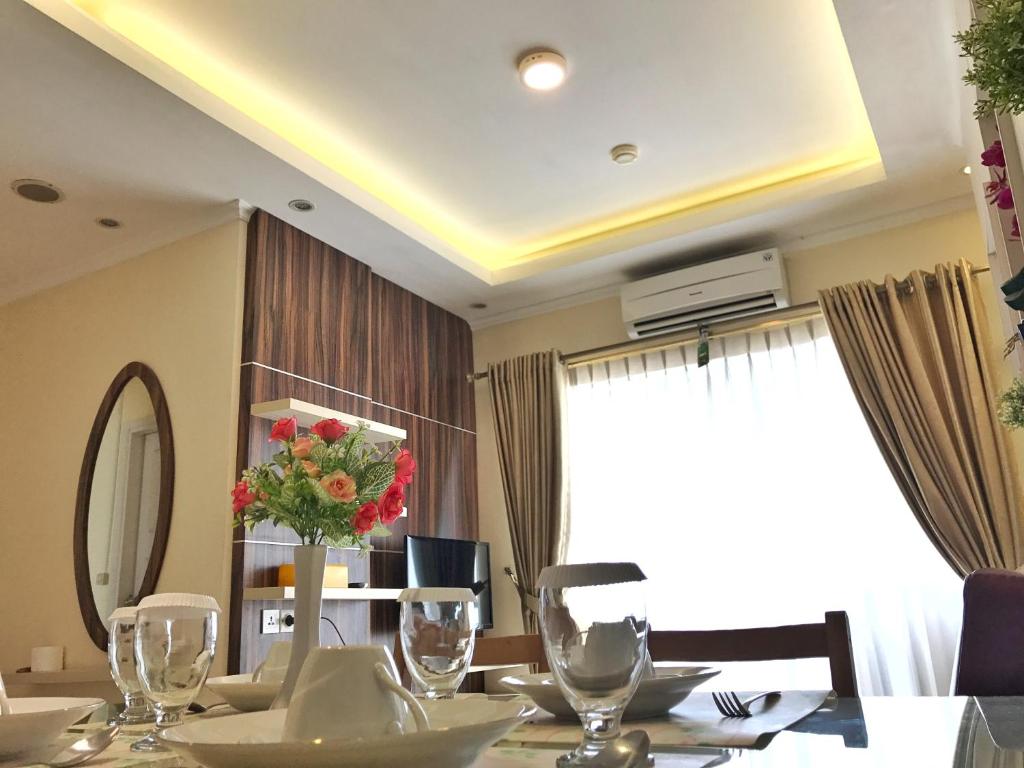 una mesa de comedor con un jarrón de flores. en Ravarine Suite Apartment, en Yakarta