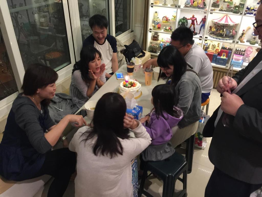 a group of people standing around a table with a cake at Doll House Lodge in Hengchun South Gate