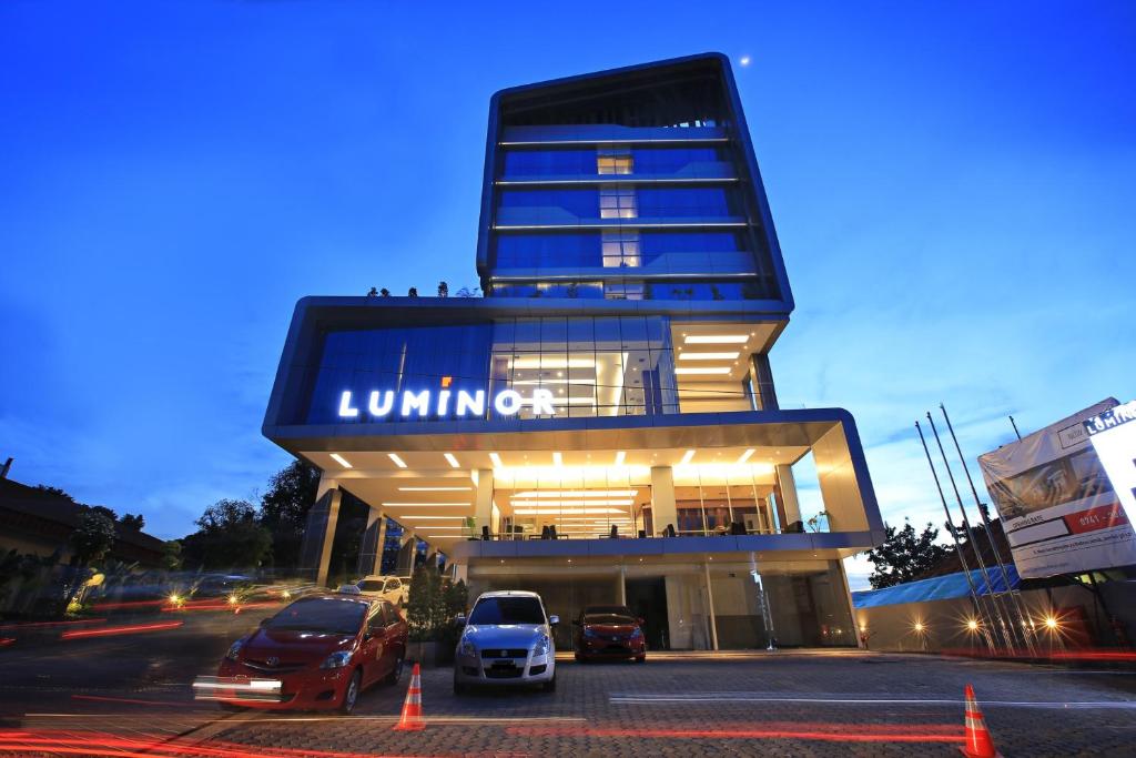 un edificio con coches estacionados en un estacionamiento en Luminor Hotel Jambi Kebun Jeruk By WH en Jambi