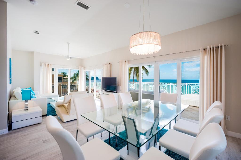 a living room with a glass table and white chairs at Regal Beach Club in George Town