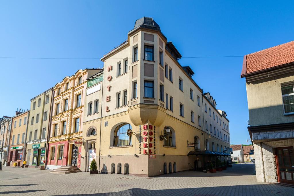 a building on a street in a city at Hotel Bartis in Bartoszyce