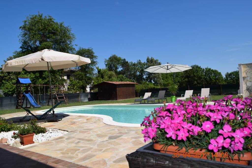 einen Pool mit rosa Blumen und einem Sonnenschirm in der Unterkunft Villa Posta Vecchia in Loreo