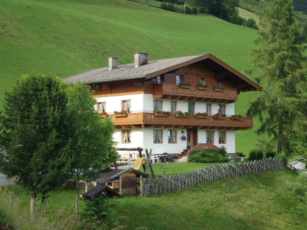 a large house in a field with a fence at Pension Grubhof in Stuhlfelden